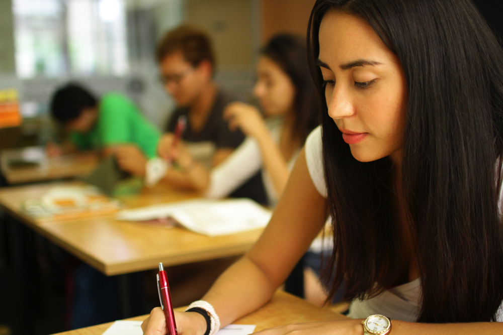 Студент за партой. Фотобанк экзамен. Студент пишет. Фон для опроса. Подготовка к поступлению в вуз.